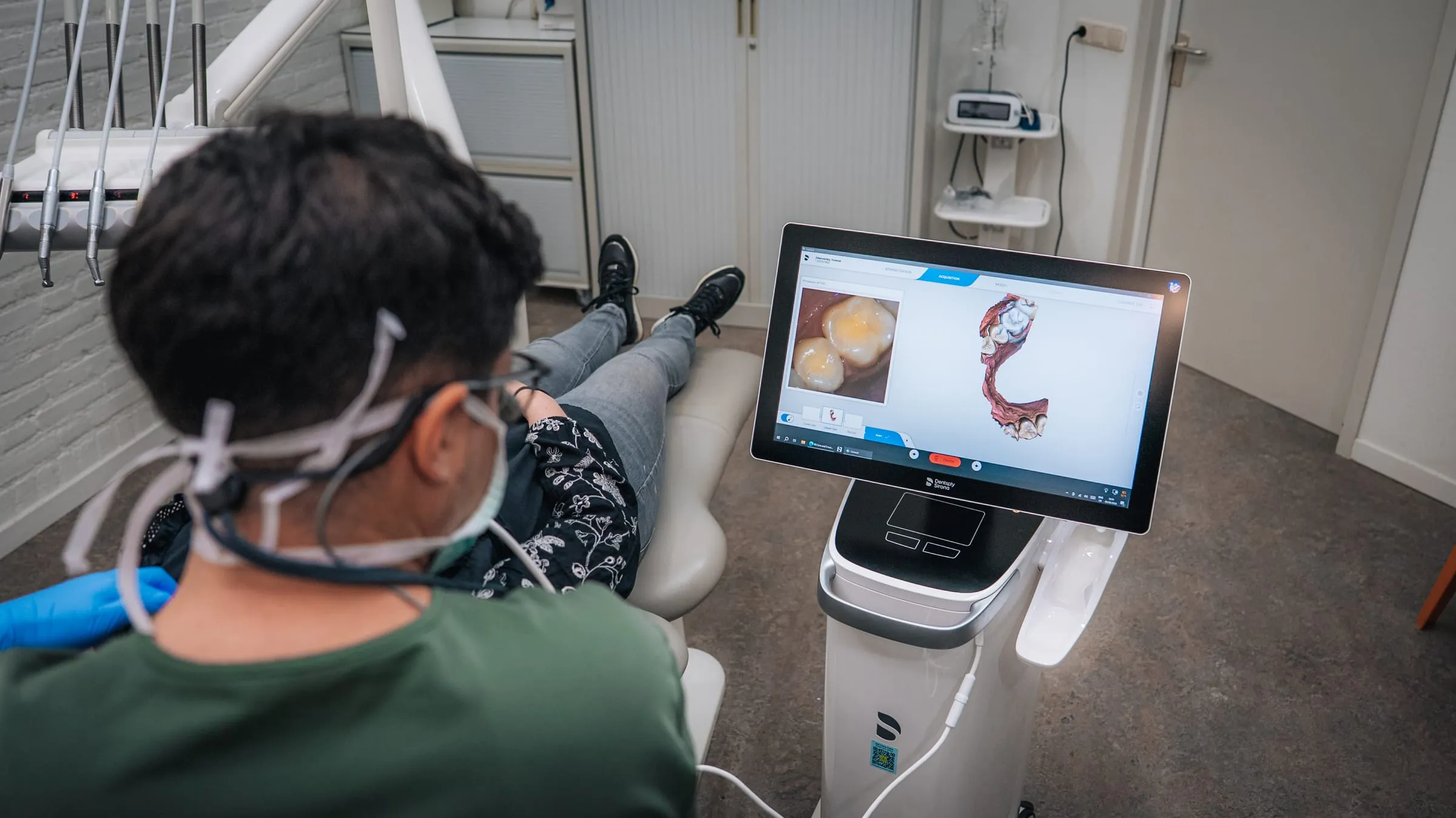 Patiënt in de behandelstoel bekijkt de 3D-scan van het gebit op het scherm